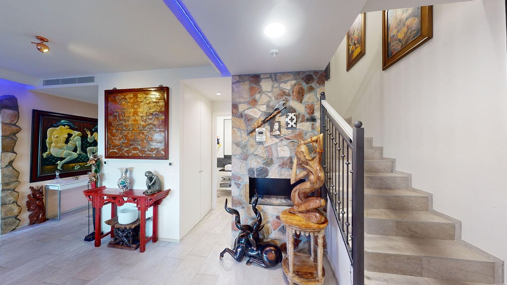 Interior of a living room with a fireplace, stone finish, and staircase in a townhouse, Luštica, Montenegro.