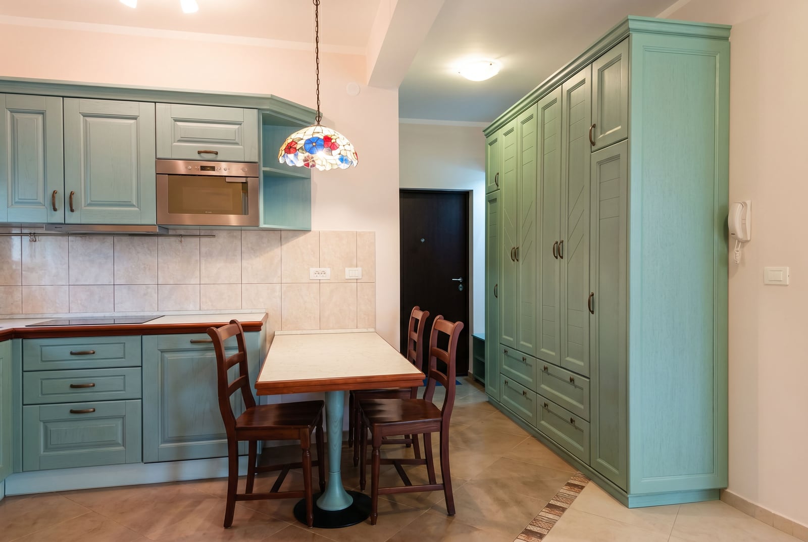 Kitchen interior in an apartment in Bar, Montenegro: mint-colored cabinetry, dining area, and a classic-style built-in wardrobe.