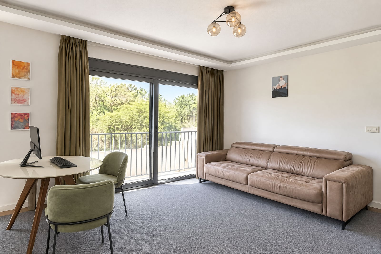 Living room with a brown sofa, round desk, green chairs, and sliding glass door to balcony.