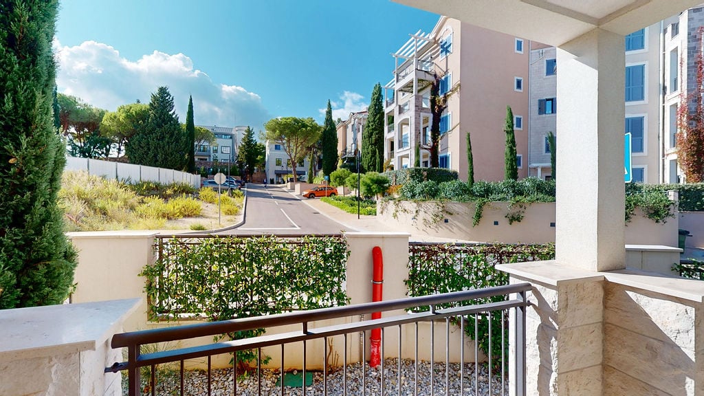 View from the balcony of a modern apartment in Luštica, Montenegro: landscaped residential complex grounds, greenery, and residential buildings.