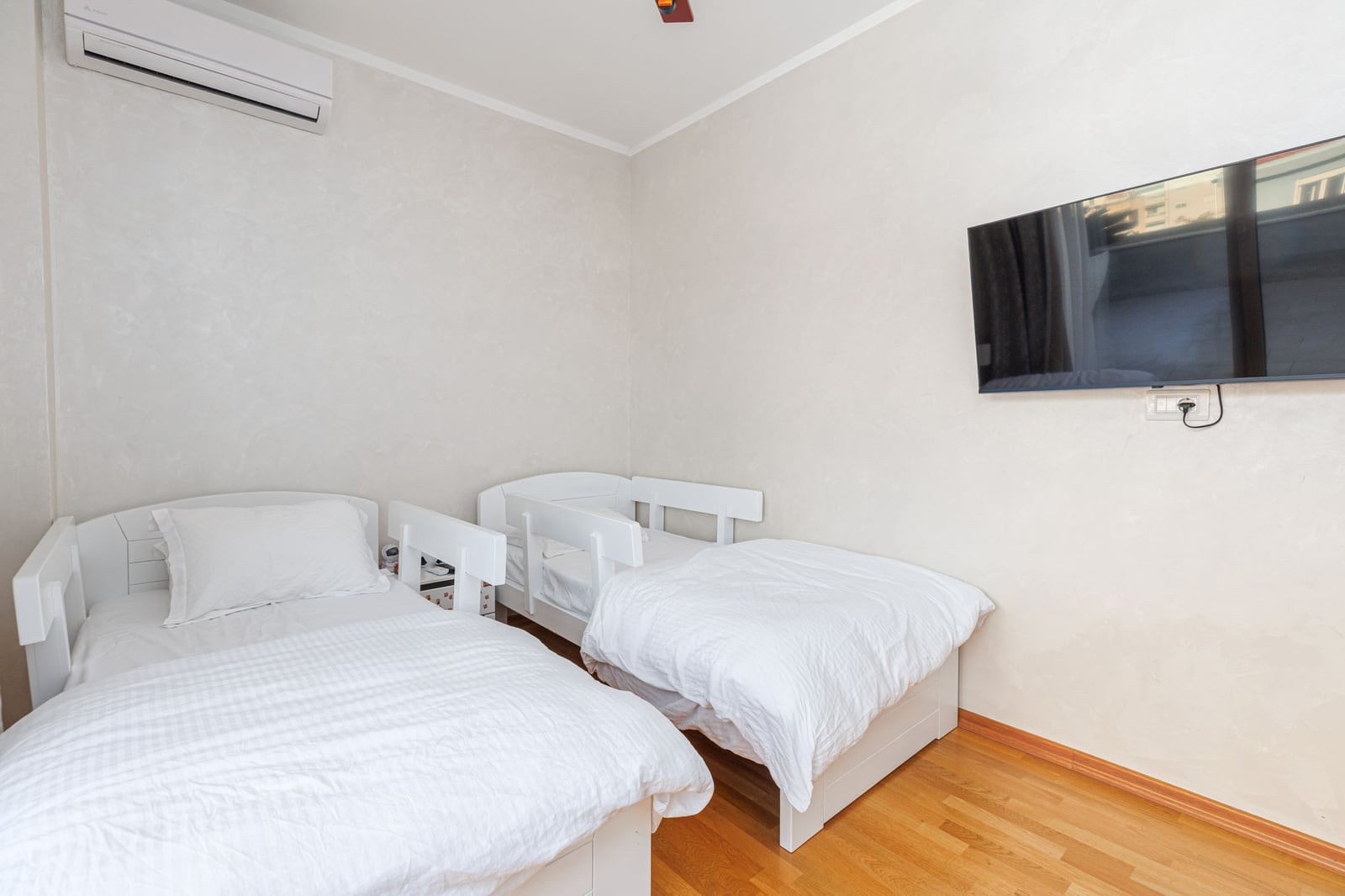 Children's bedroom with two white beds, TV, and air conditioning in a penthouse, Becici, Montenegro.