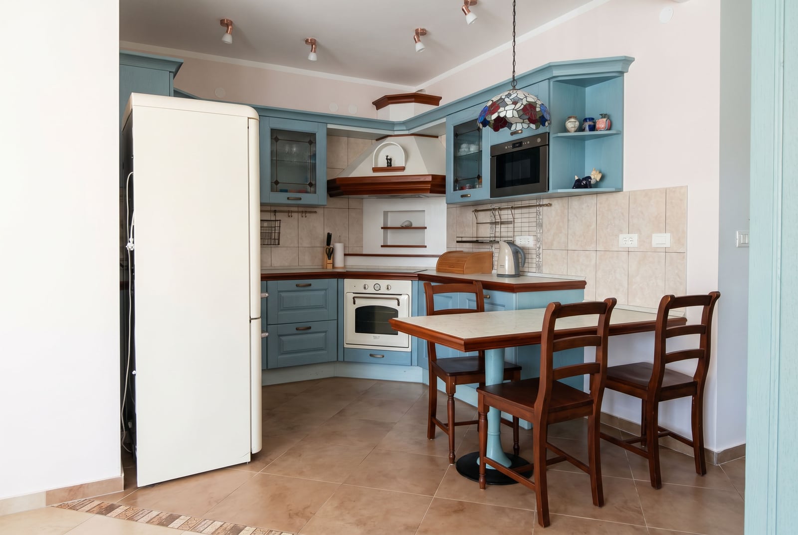 Cozy kitchen with blue cabinetry and a dining area in an apartment for sale in Bar, Montenegro.