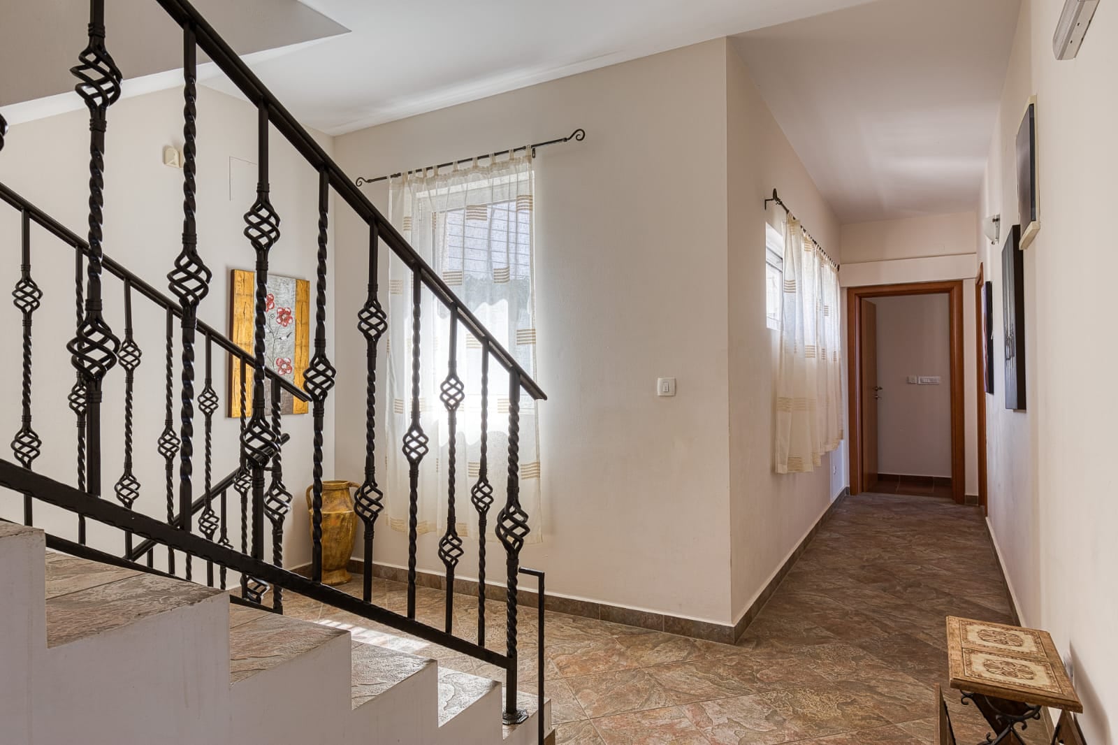 Interior of a villa in Bečići, Montenegro: wrought-iron staircase, bright tiled hallway, and classic-style decor.