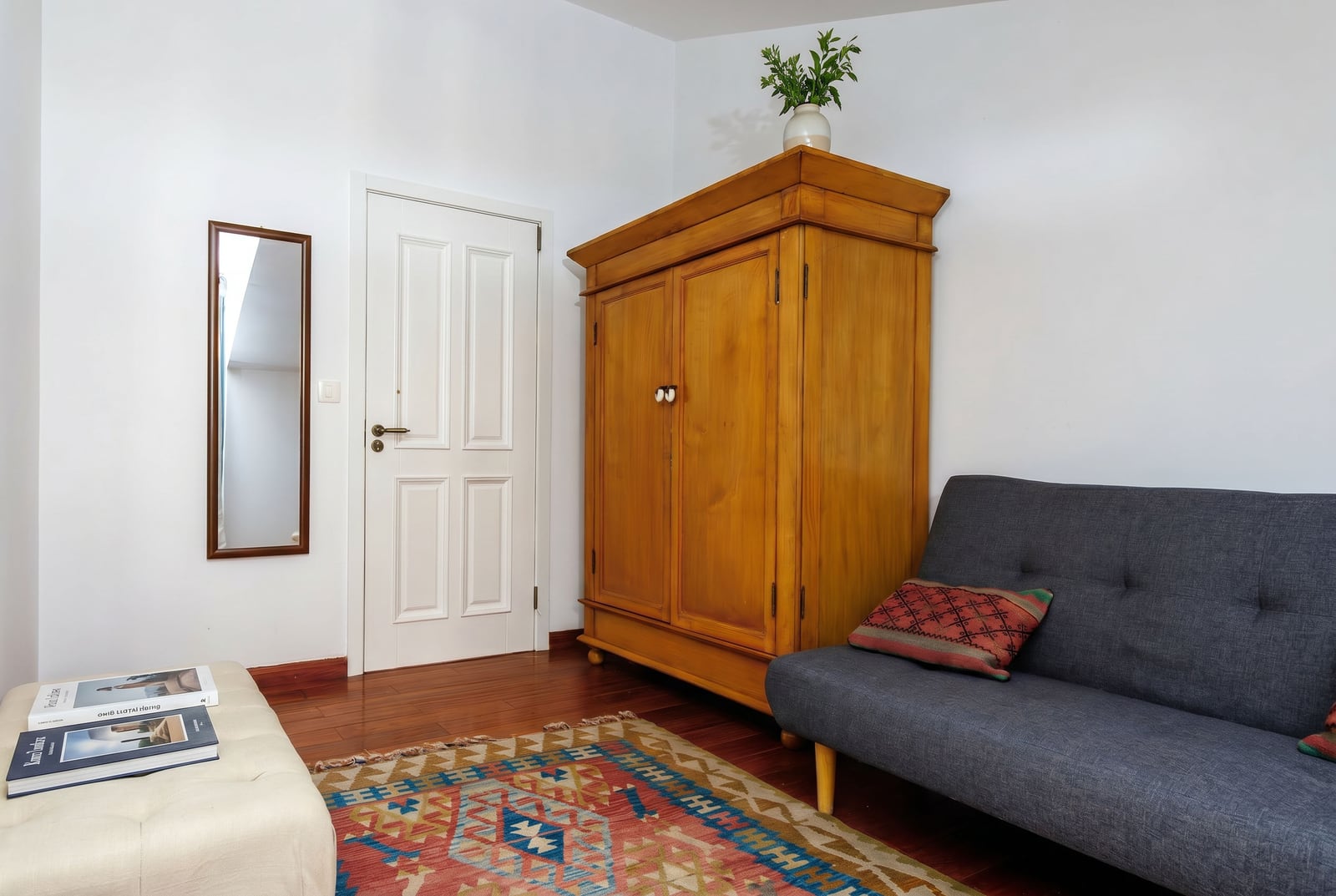 Living room in a penthouse in Risan, Montenegro: gray sofa, massive wooden cabinet, carpet, and light interior.