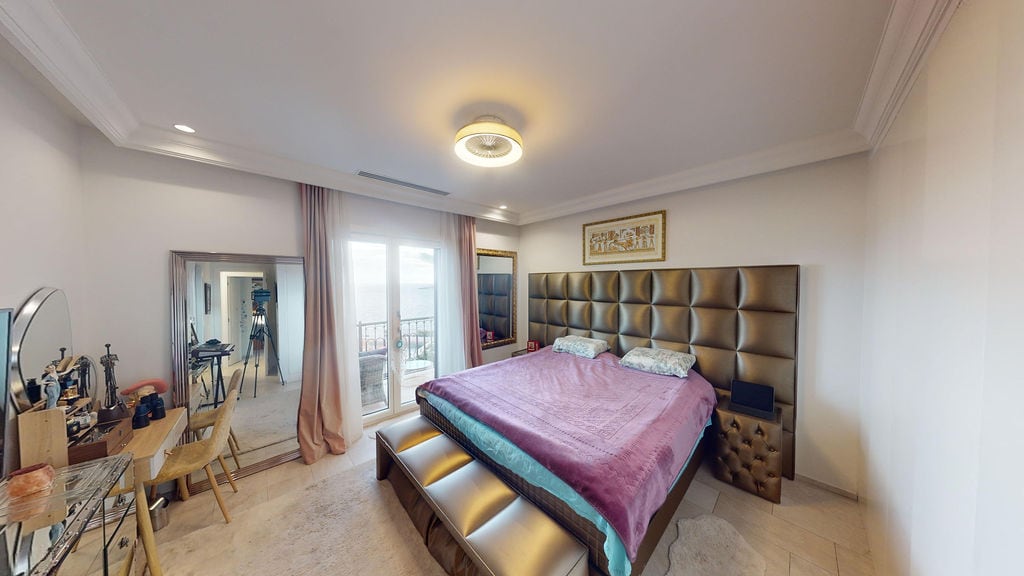 Bedroom in a townhouse in Luštica, Montenegro: double bed with upholstered headboard, vanity table, and sea view.