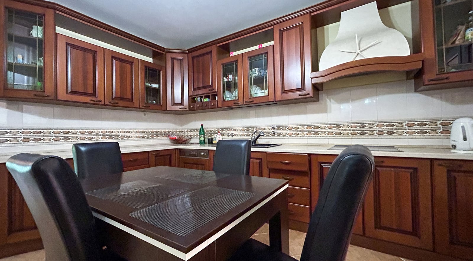 Cozy kitchen with wooden cabinetry and dining area in a villa in Dobrota, Montenegro. House interior No. 2609.