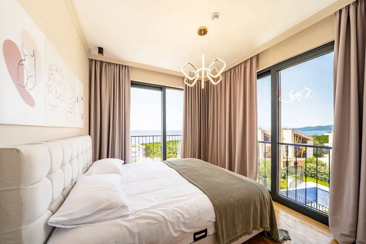 Modern bedroom in a villa in Reževići, Montenegro: panoramic windows, sea and pool view, stylish interior.