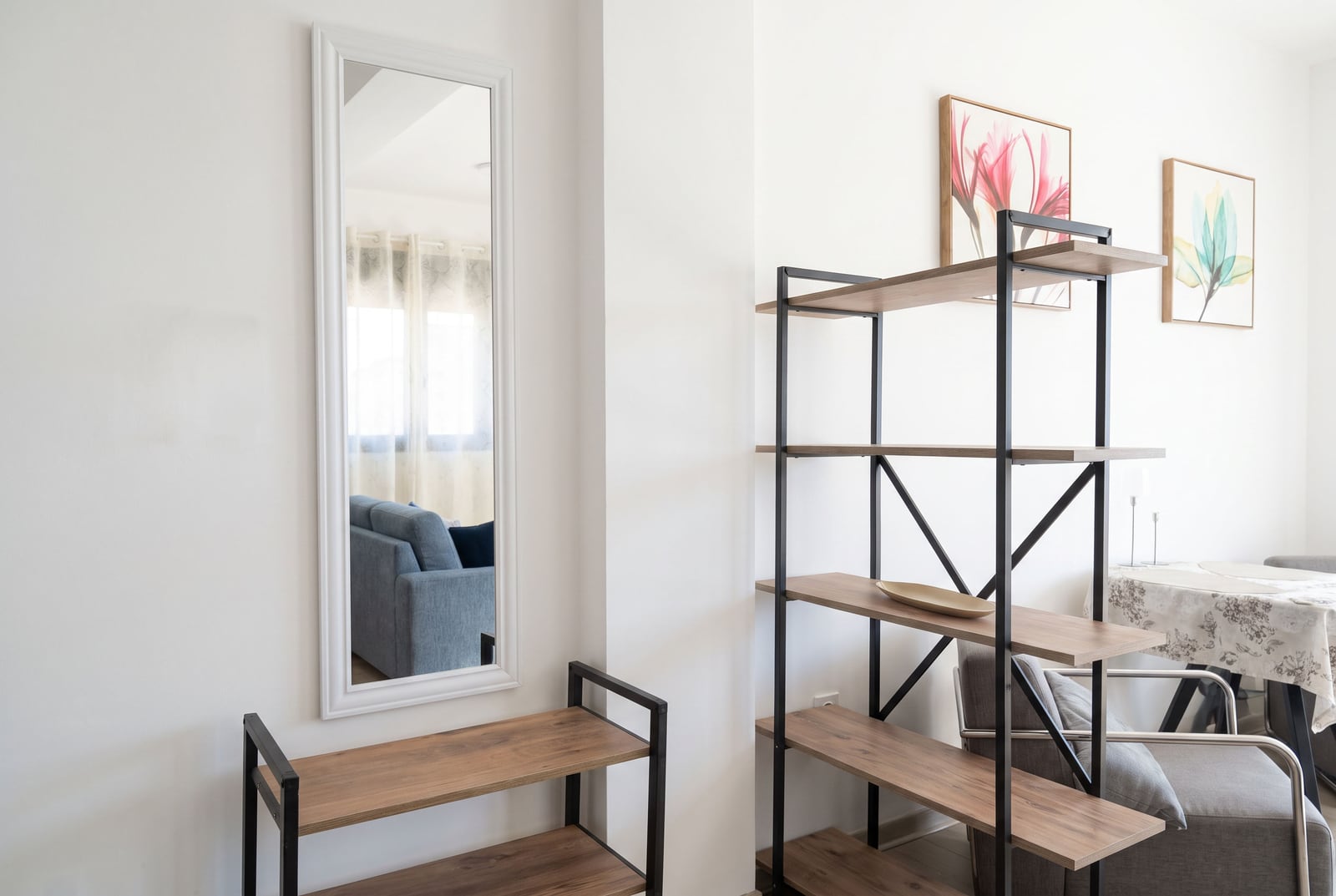 Living room interior with loft-style furniture, a mirror, and a shelving unit in an apartment in Budva, Montenegro