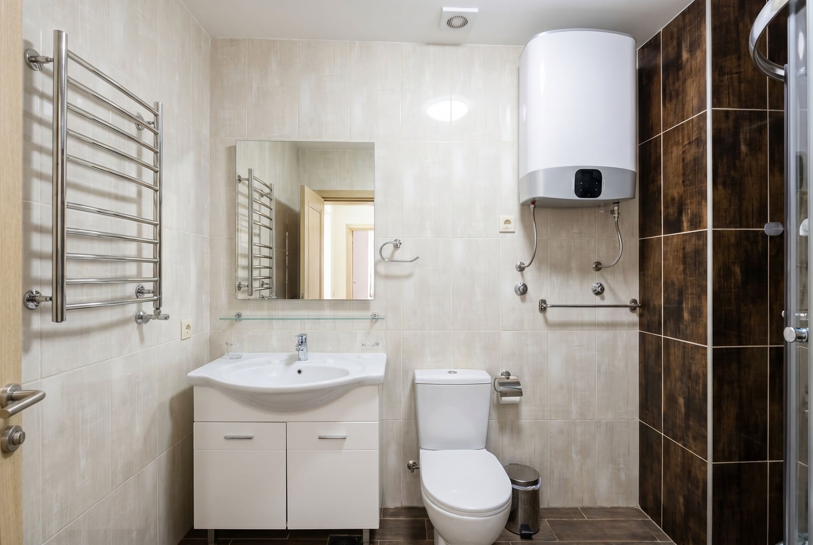 Modern bathroom in an apartment in Becici, Montenegro: light-colored tiles, shower cabin, water heater, and sanitary ware.
