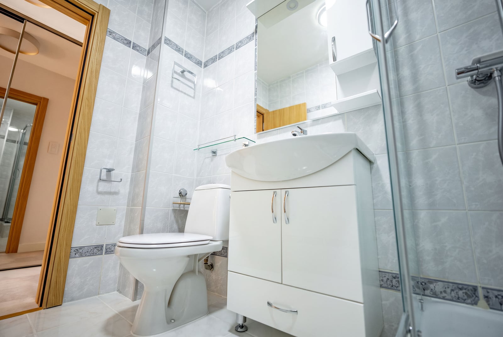 Bright bathroom in an apartment in Sveti Stefan, Montenegro: white tiles, shower cabin, and a vanity unit with a sink.