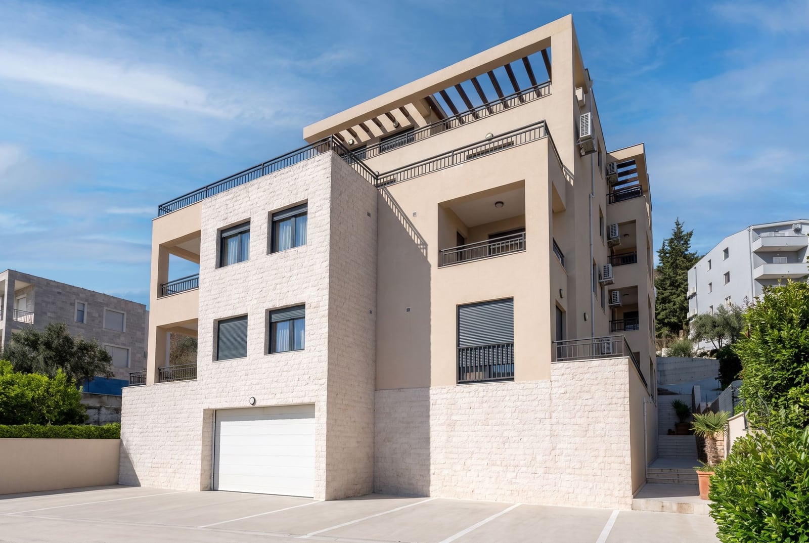 Modern residential building with parking and terraces in Tivat, Montenegro, featuring a stone and plaster facade.