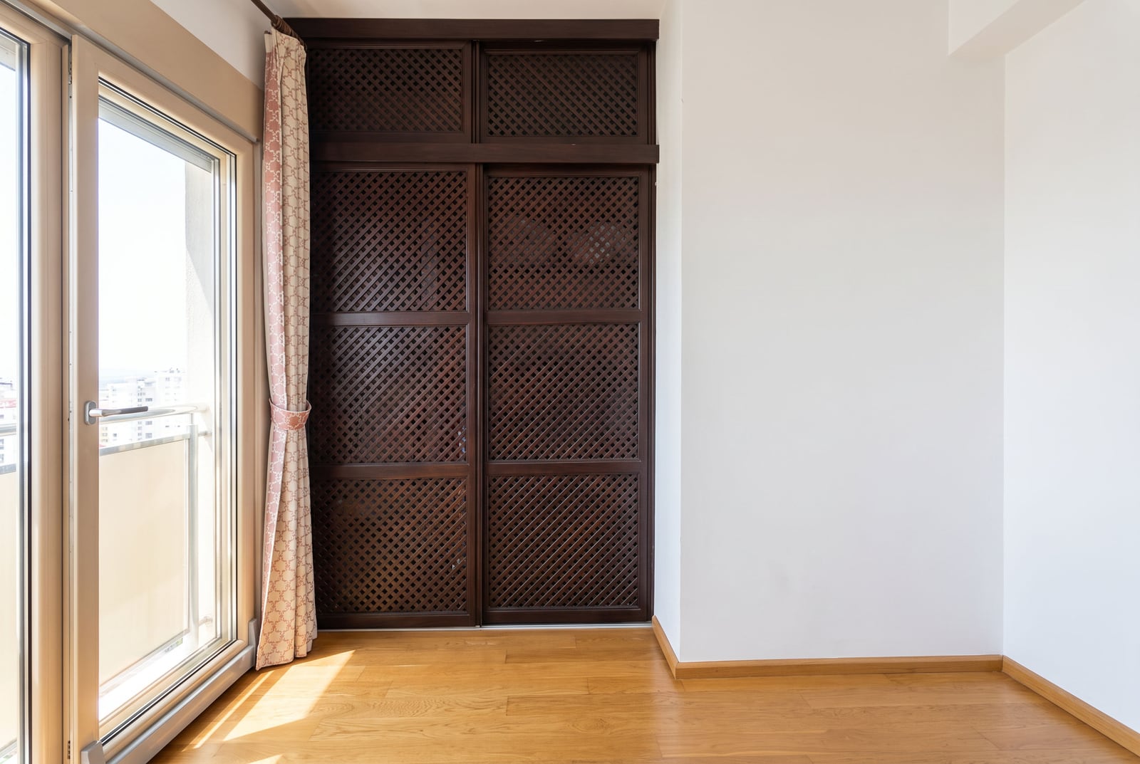 Built-in dark wardrobe with slatted doors and a panoramic window in the bedroom of an apartment in Bečići, Montenegro.