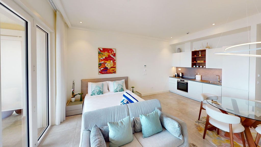 Modern studio with kitchen and bedroom in the Luštica residential complex, Montenegro: bright interior, panoramic windows, and stylish furniture.