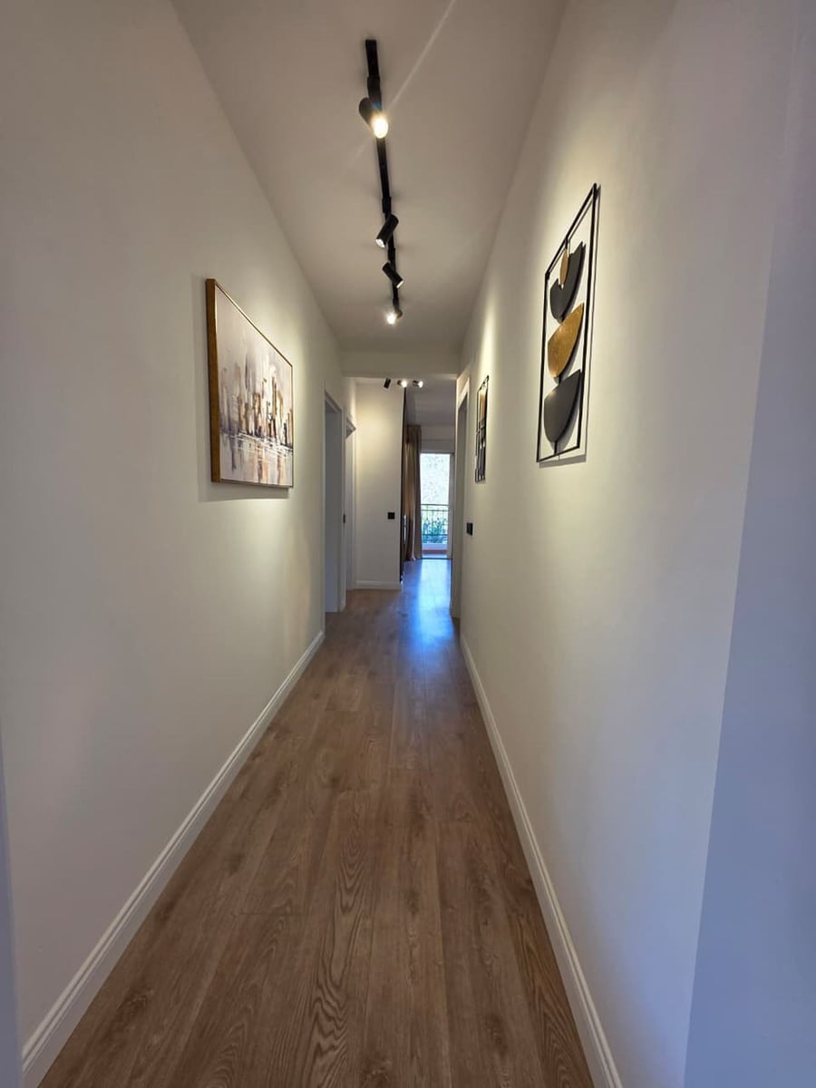 Bright hallway in a modern apartment in Bečići, Montenegro: wood-look laminate flooring, track lighting, and wall decor.