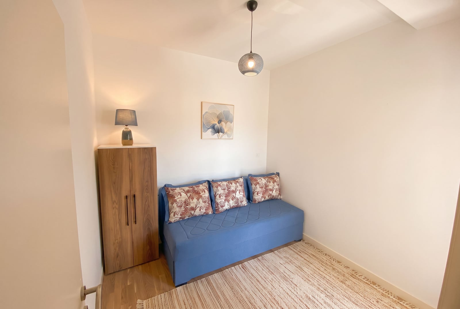 Cozy bedroom with a blue sofa and wooden wardrobe in an apartment in Dobrota, Montenegro. Modern room interior.
