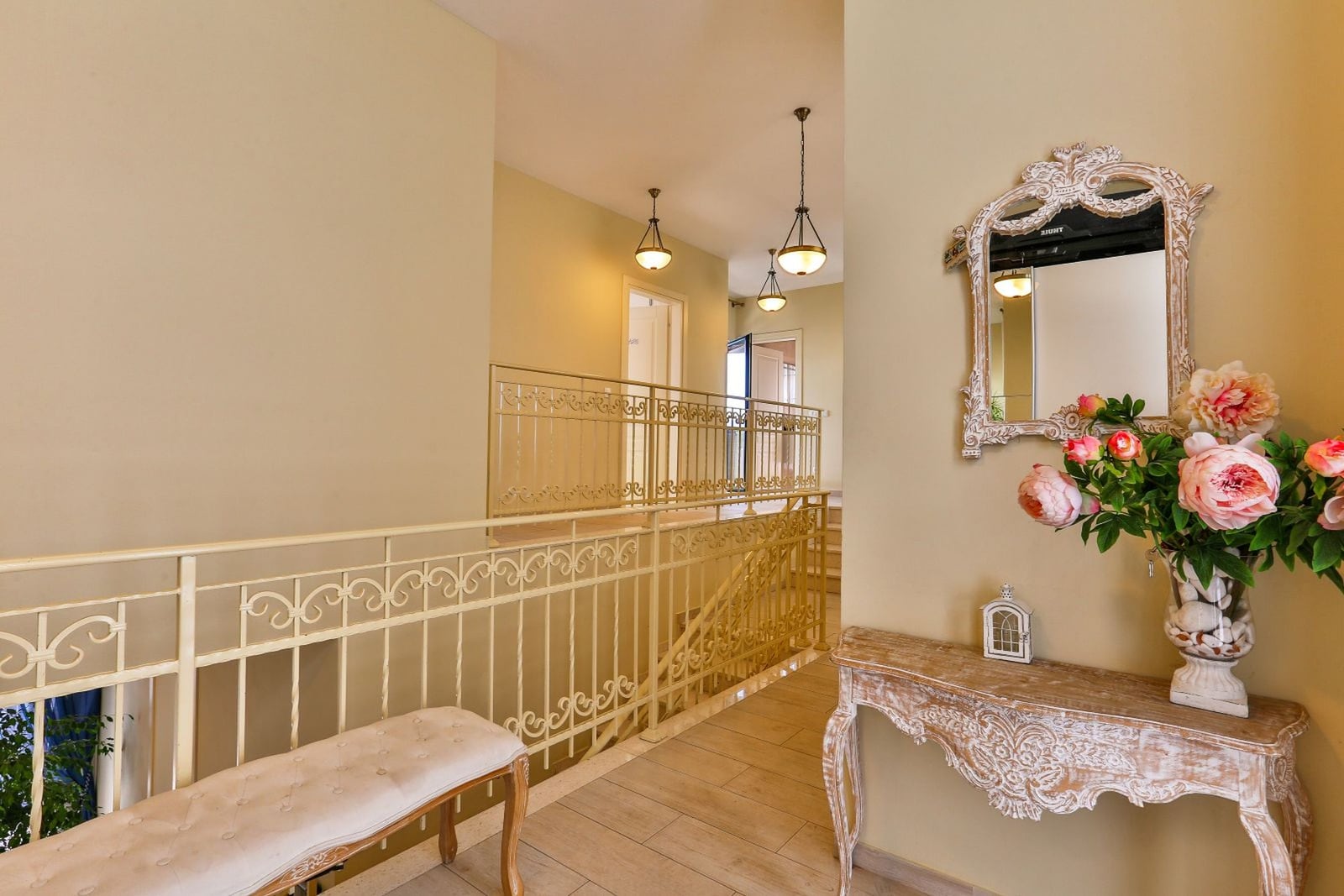 Bright hallway of a villa in Tivat, Montenegro: wrought iron railings, vintage console, mirror, and classic-style decor.