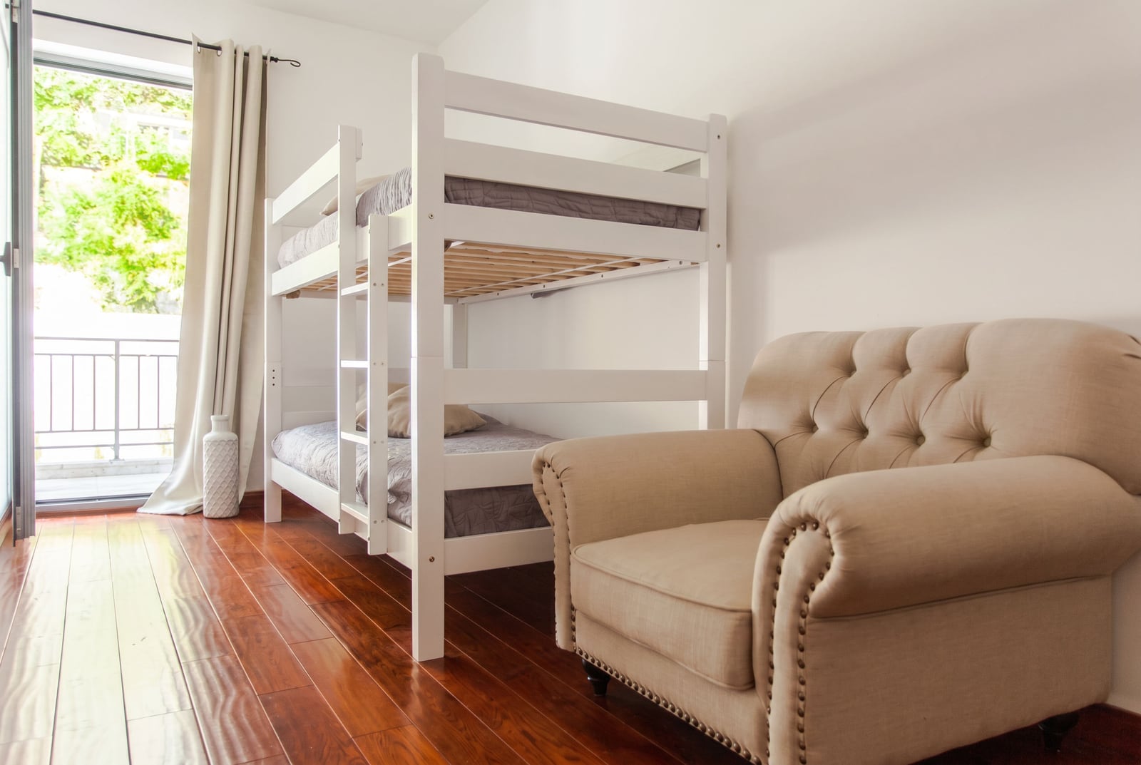 Bedroom with a bunk bed and an armchair in an apartment in Risan, Montenegro, with access to a balcony and parquet flooring.