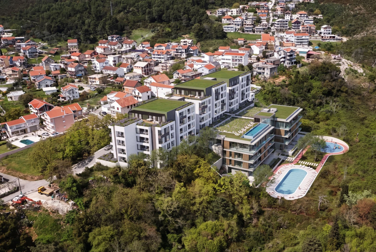 Aerial view of a modern residential complex with green roofs and pools situated in a forested area.