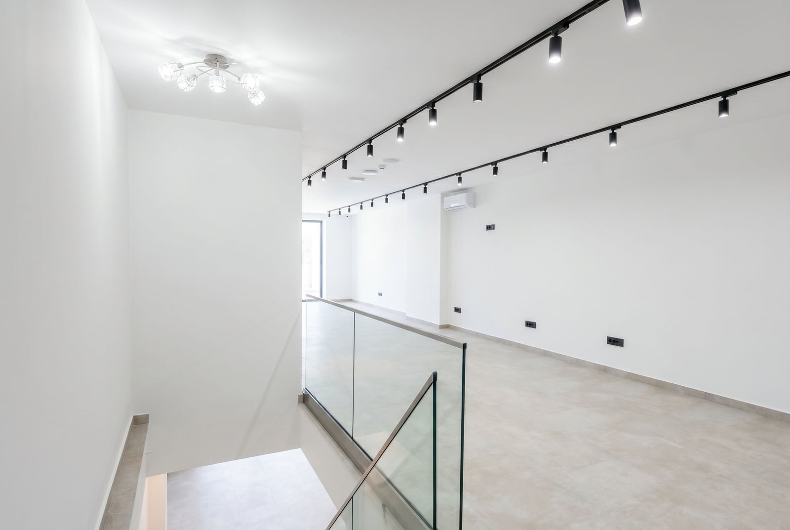 Bright office in Budva, Montenegro: spacious room with white walls, track lighting, and glass partitions.
