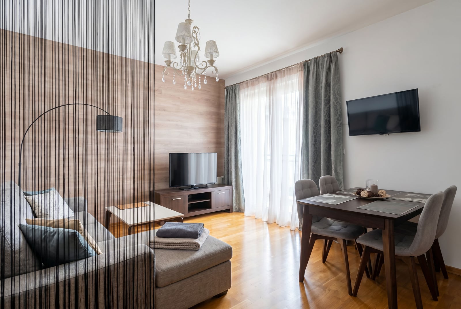 Living room in an apartment in Budva, Montenegro: modern furniture, dining area, wooden floor, and panoramic window.