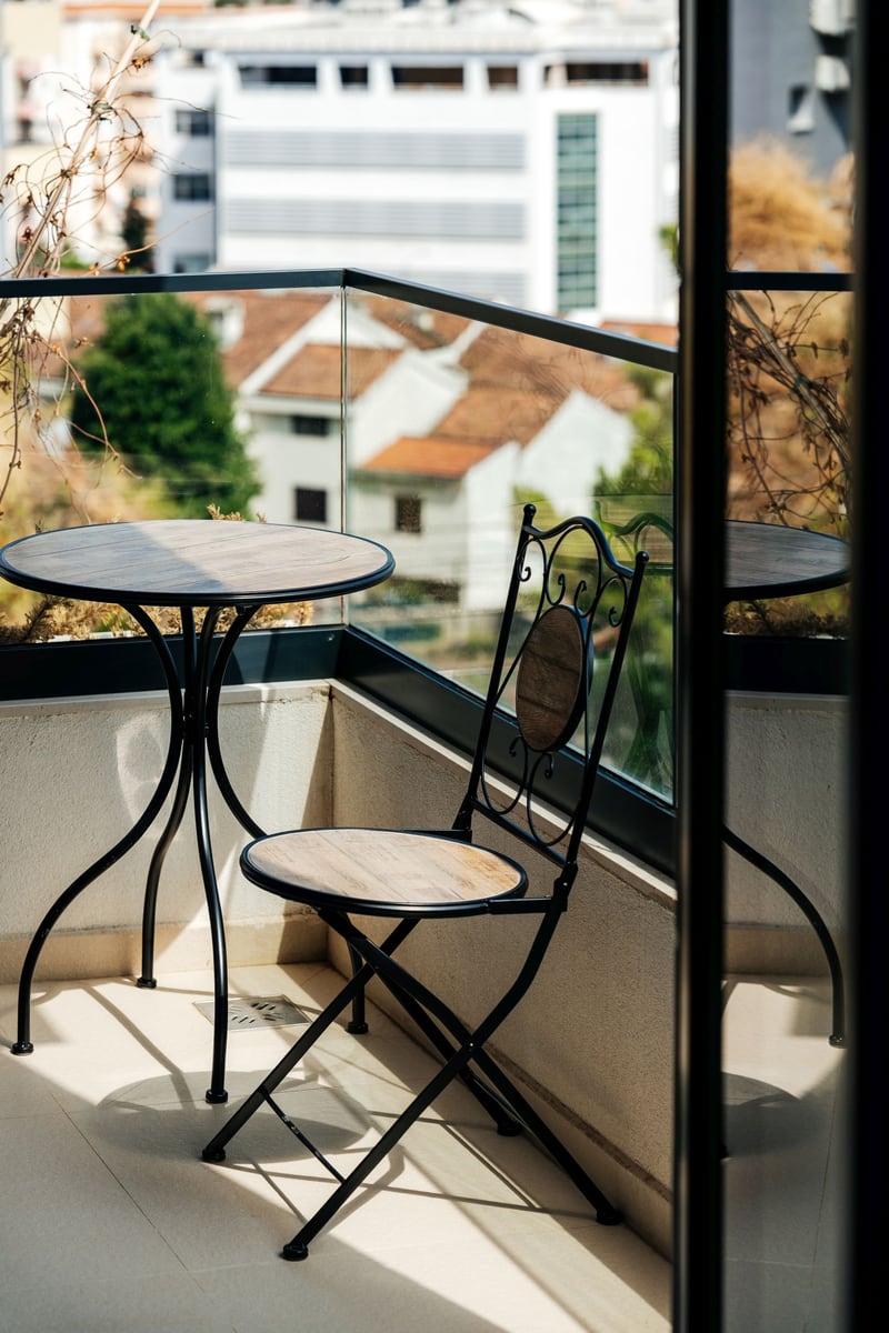 Cozy balcony with wrought-iron furniture and panoramic city views in a residential complex, Budva, Montenegro.