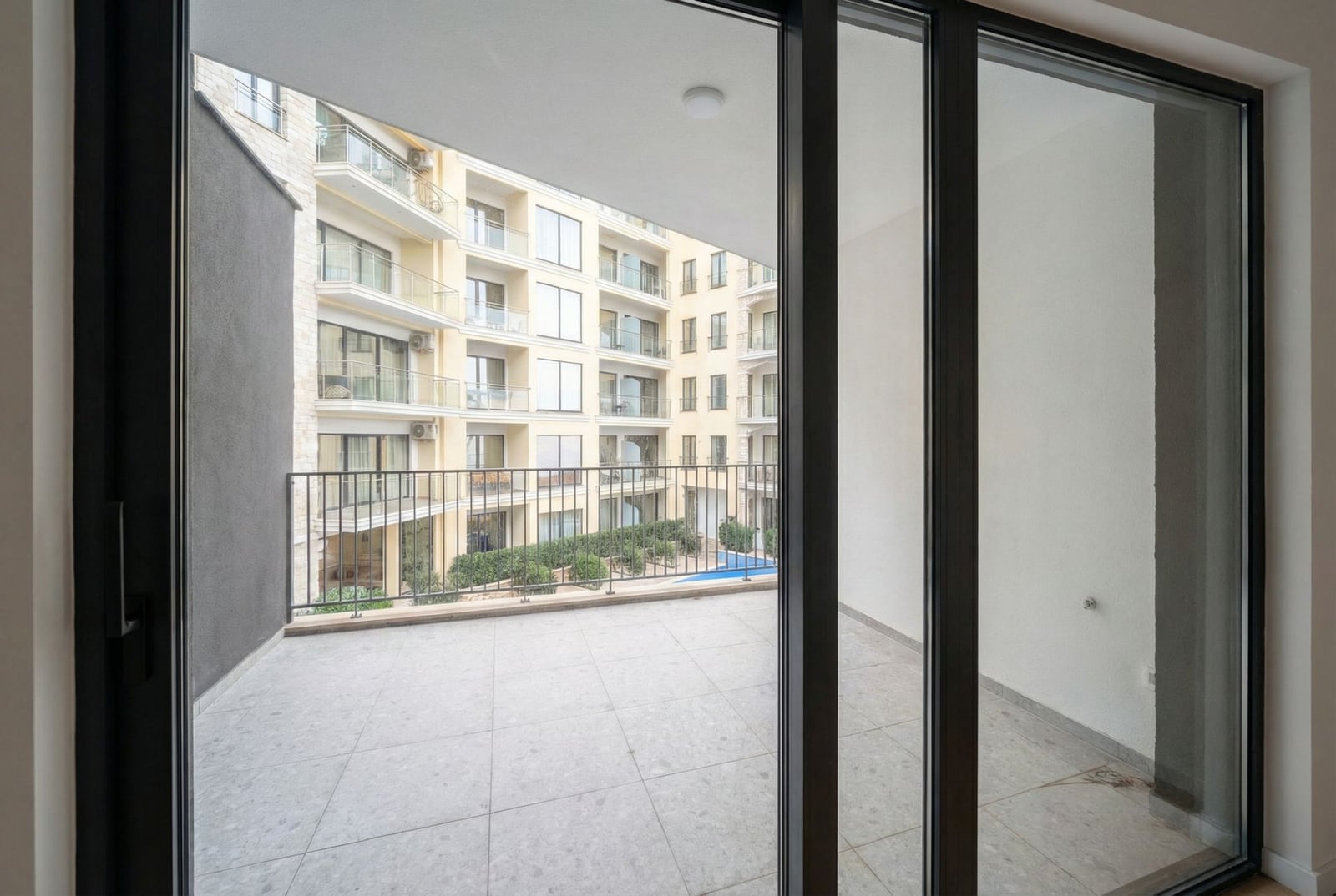 Spacious balcony with panoramic views of the residential complex in Becici, Montenegro, with modern finishes and glazing.