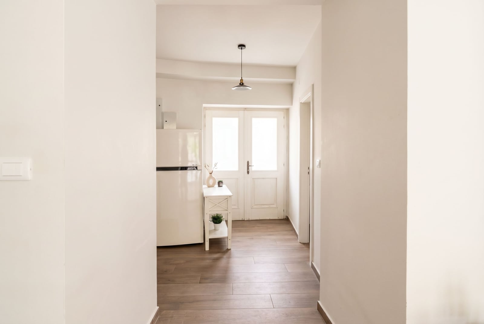 Bright kitchen in an apartment in Budva, Montenegro: white refrigerator, wooden floor, and access to the terrace through the doors.