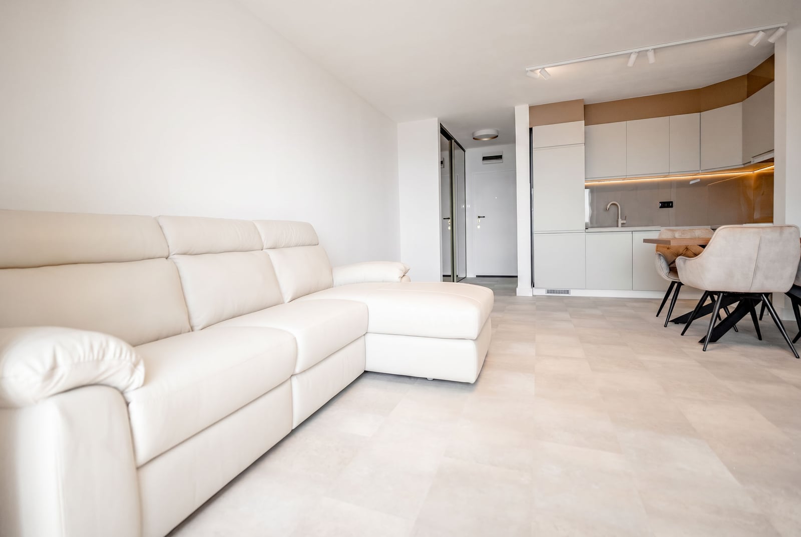 Modern living room with a white leather sofa and kitchen in an apartment, Sveti Stefan, Montenegro. Bright interior with furniture.