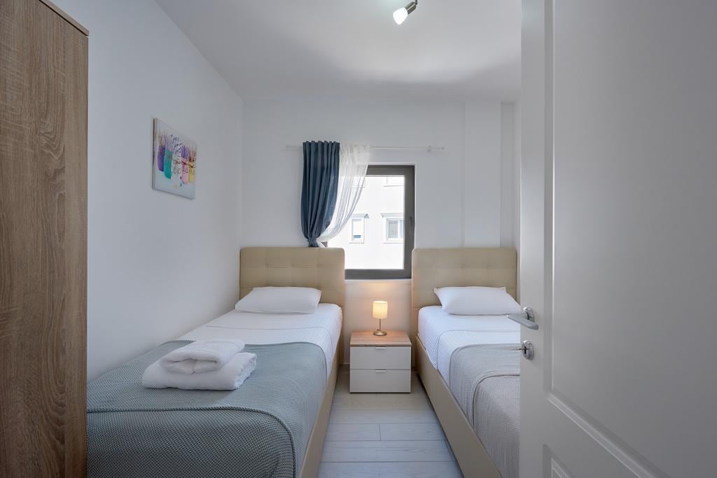 Bedroom with two single beds in an apartment, Pržno, Montenegro: bright interior, bedside table, and window.