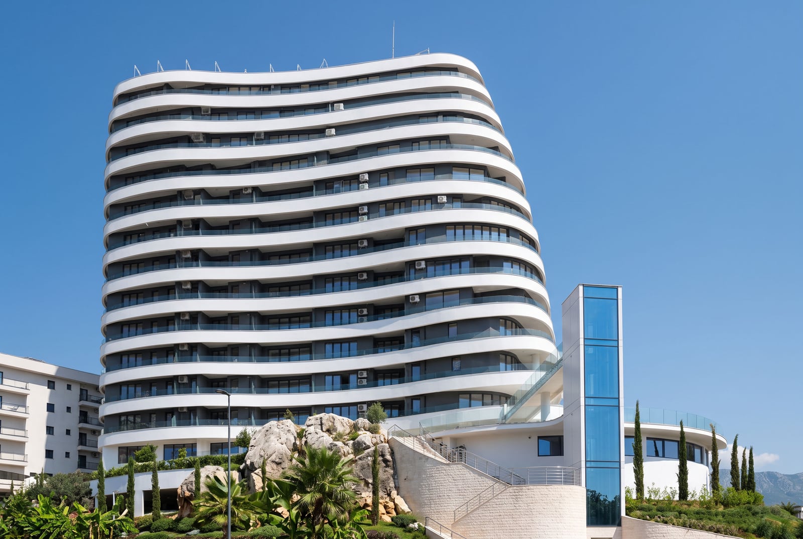 Modern residential complex with panoramic balconies in Bečići, Montenegro: view of the building facade and surrounding area.