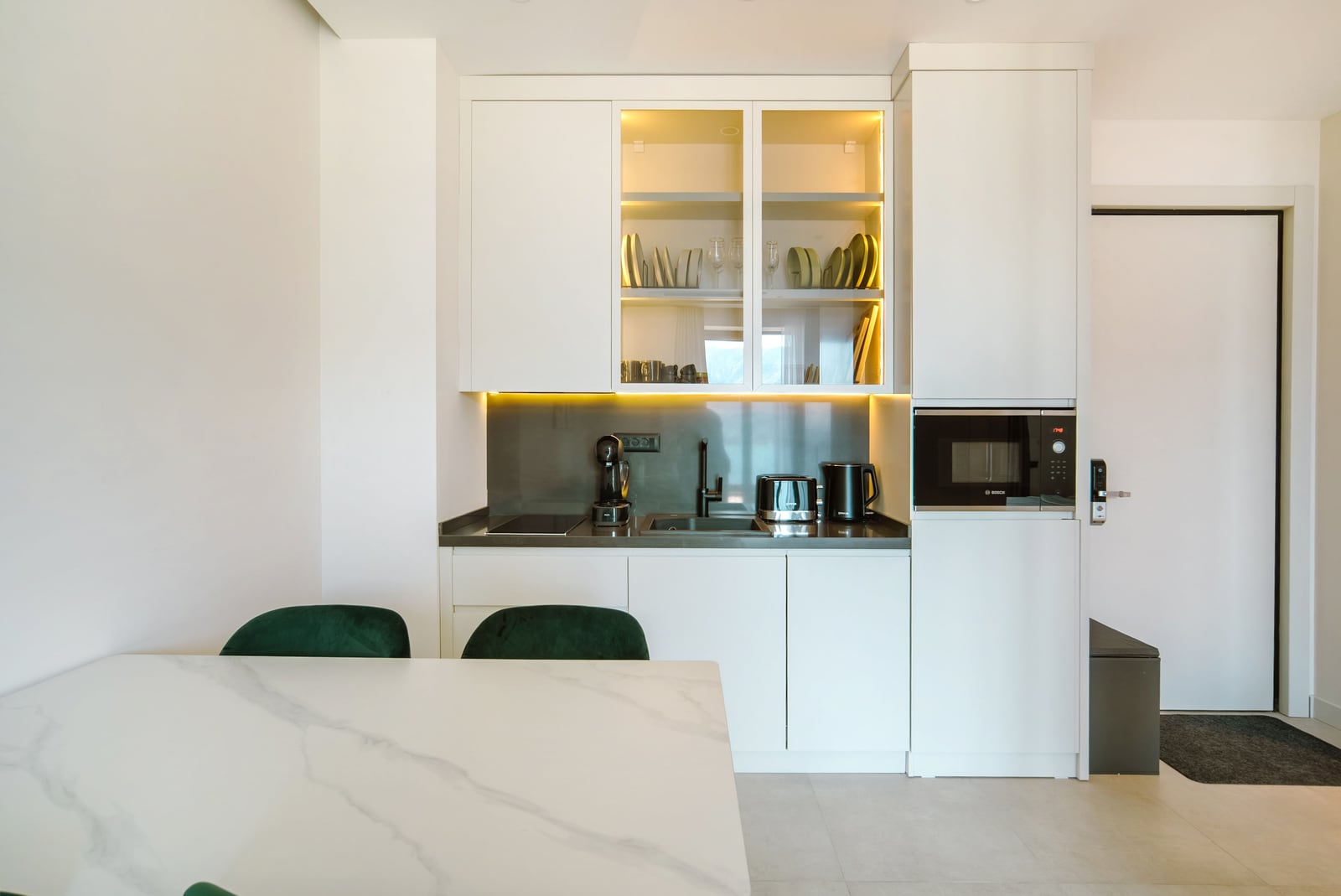 Modern white kitchen with lighting and built-in appliances in an apartment in the Bečići residential complex, Montenegro.