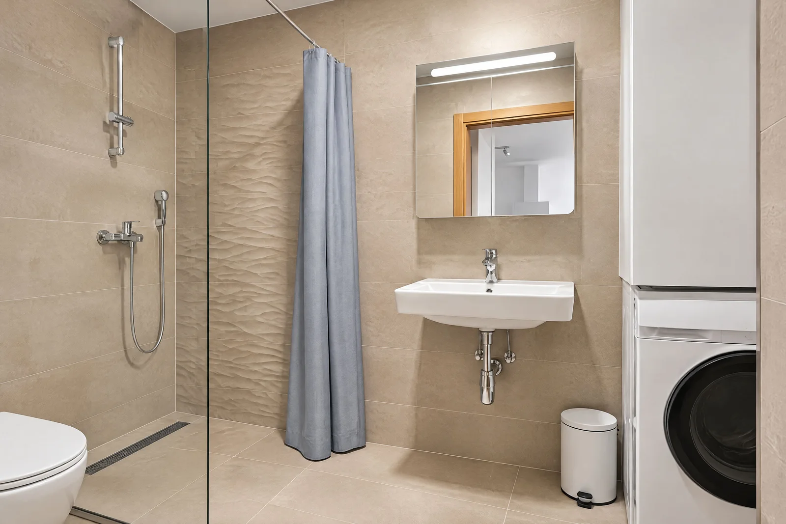Modern bathroom featuring a shower with curtain, wall-mounted sink, illuminated mirror, and washing machine.