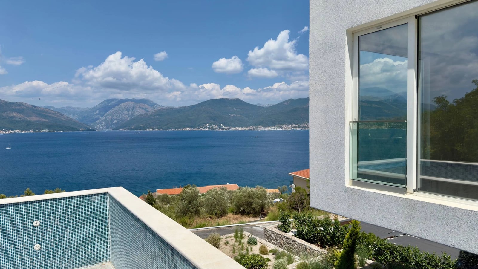 Sea and mountain view from the pool of a modern villa in Krašići, Montenegro: panoramic scenery and stylish finishes.