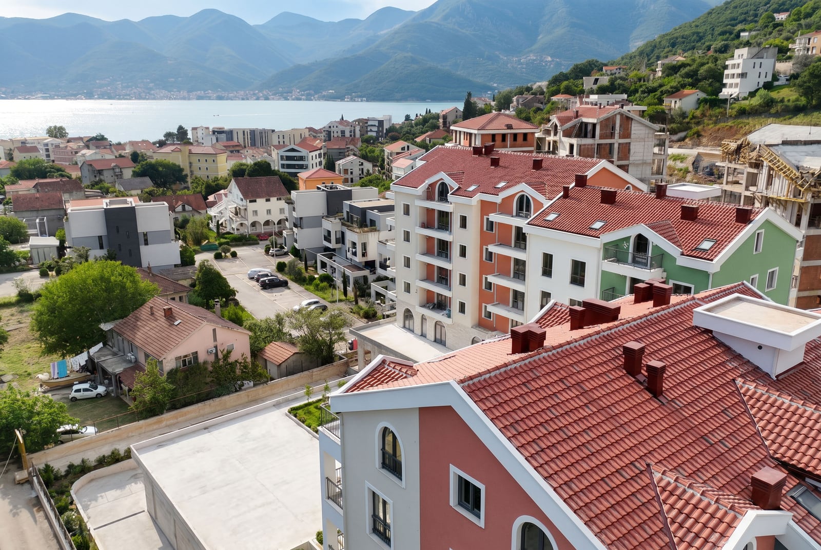 Panoramic view of a residential complex in Tivat, Montenegro: modern houses with red tiled roofs and a view of the bay.