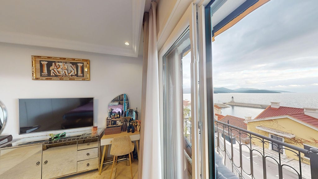Bedroom in a townhouse in Luštica Bay, Montenegro: sea view, balcony, modern furniture, and TV in the interior.