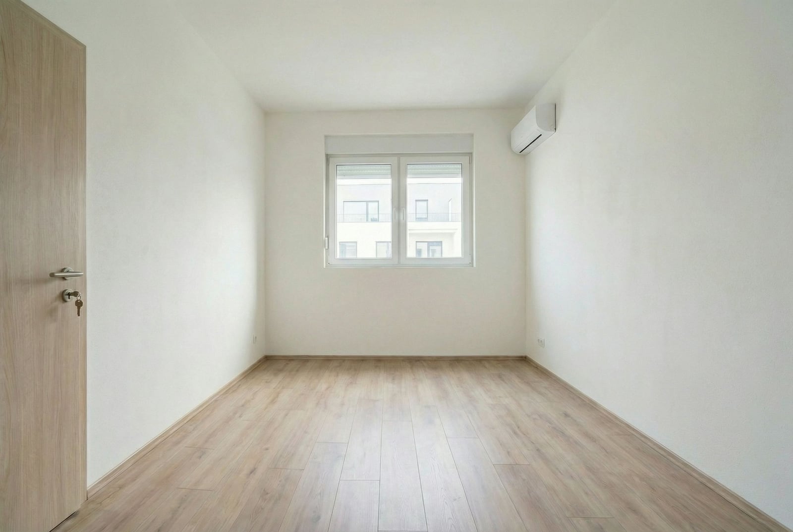 Bright empty bedroom with laminate flooring, white walls, and air conditioning in a new apartment in Budva, Montenegro.