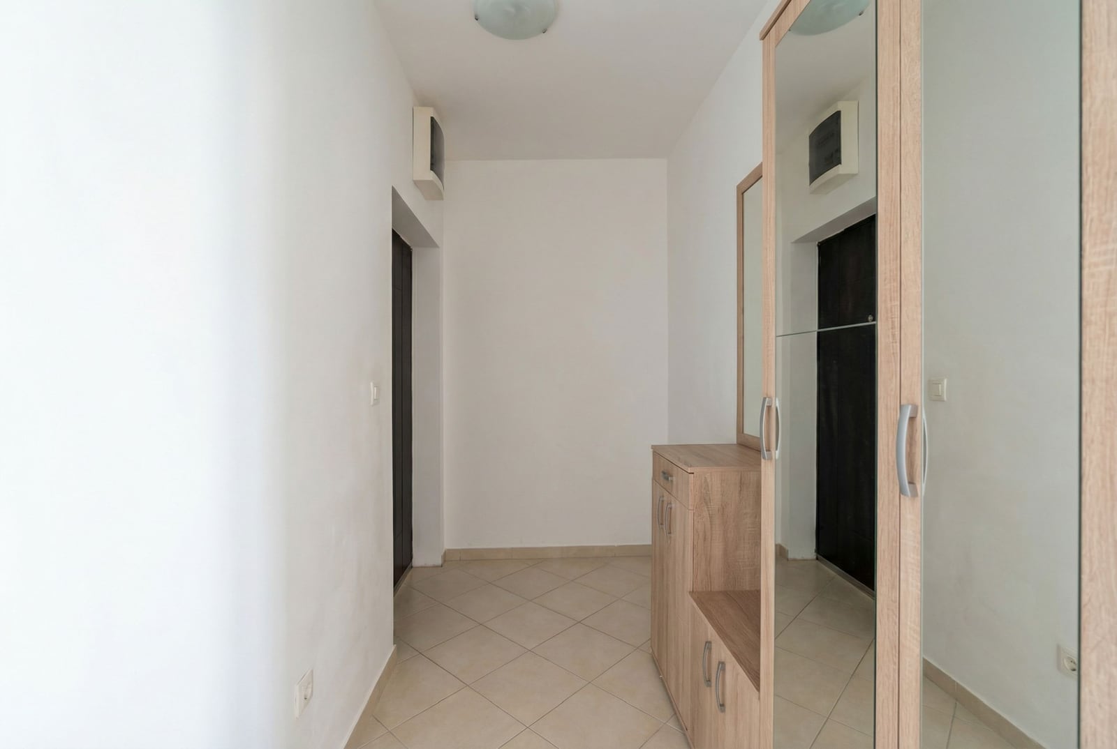 Bright entryway in an apartment in Budva, Montenegro: built-in mirrored wardrobe, tiled floor, and white walls.