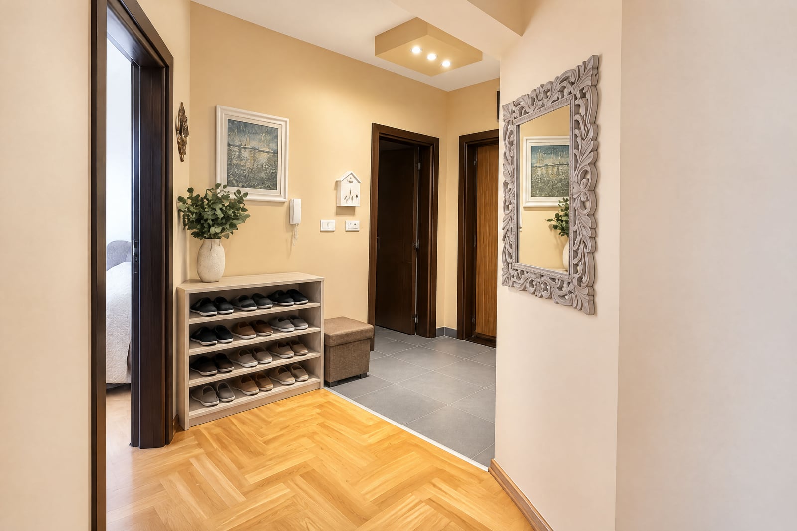 Entryway featuring a shoe rack, ornate mirror, herringbone wood floor, and hallway doors.