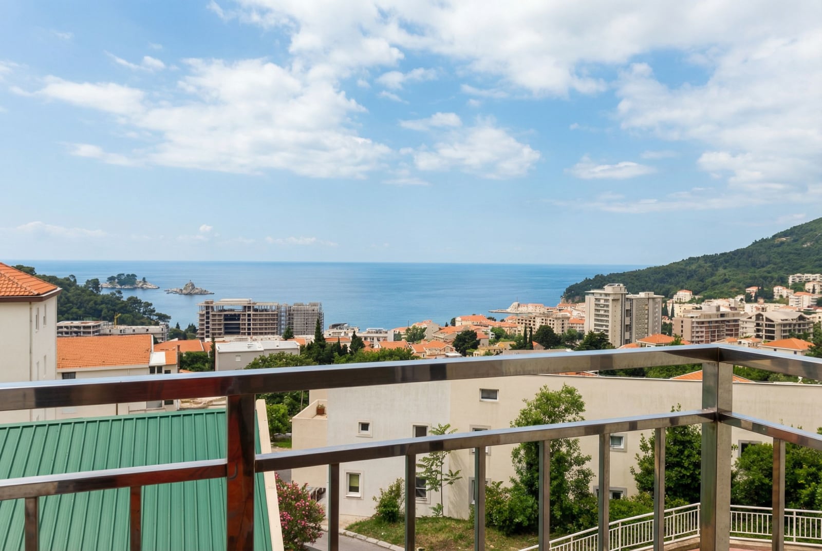 Panoramic view of the sea and the city of Petrovac, Montenegro, from the apartment balcony with modern metal railings.
