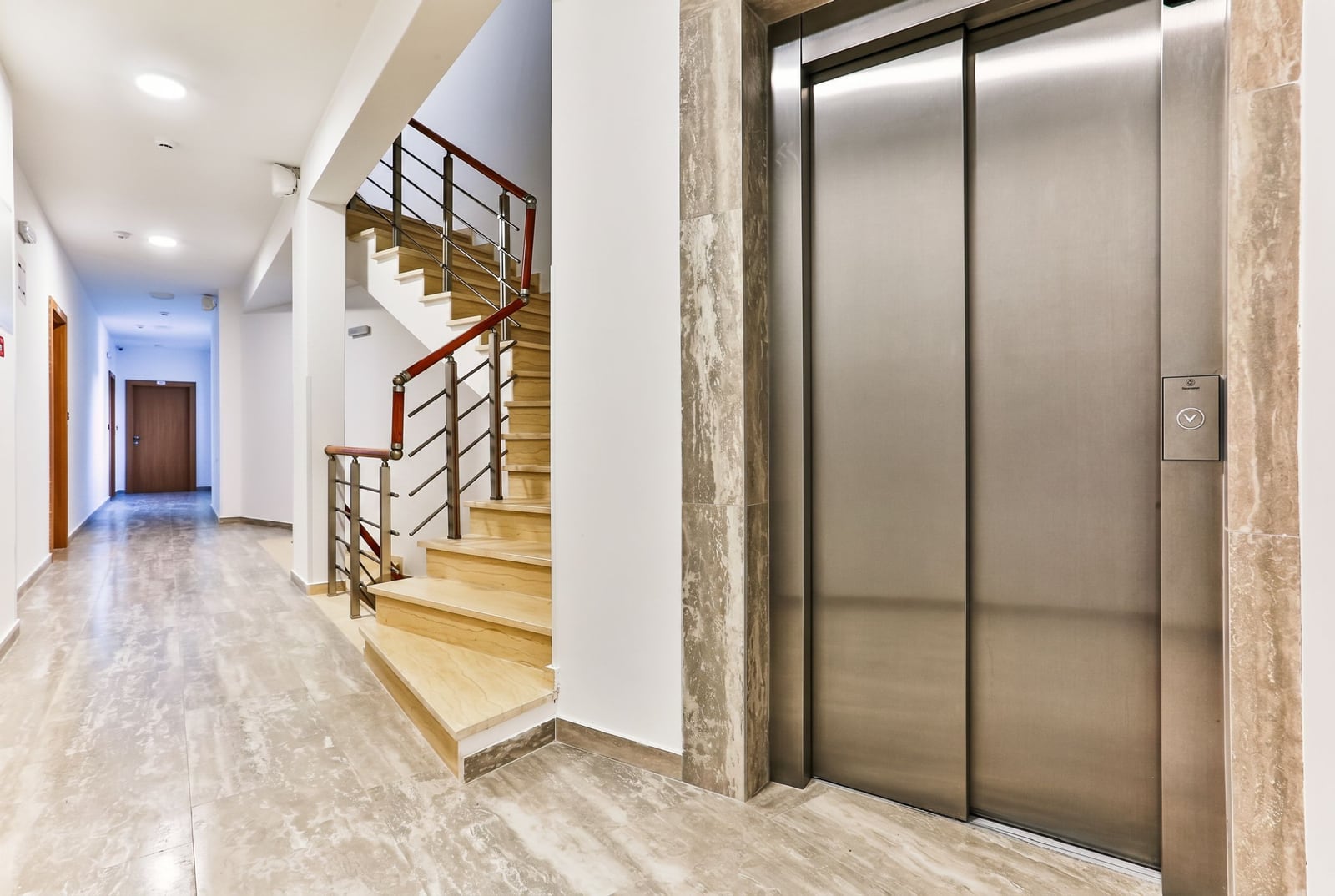 Modern entrance hall with elevator and staircase in a residential complex, Budva, Montenegro: stone finishes and a bright interior.