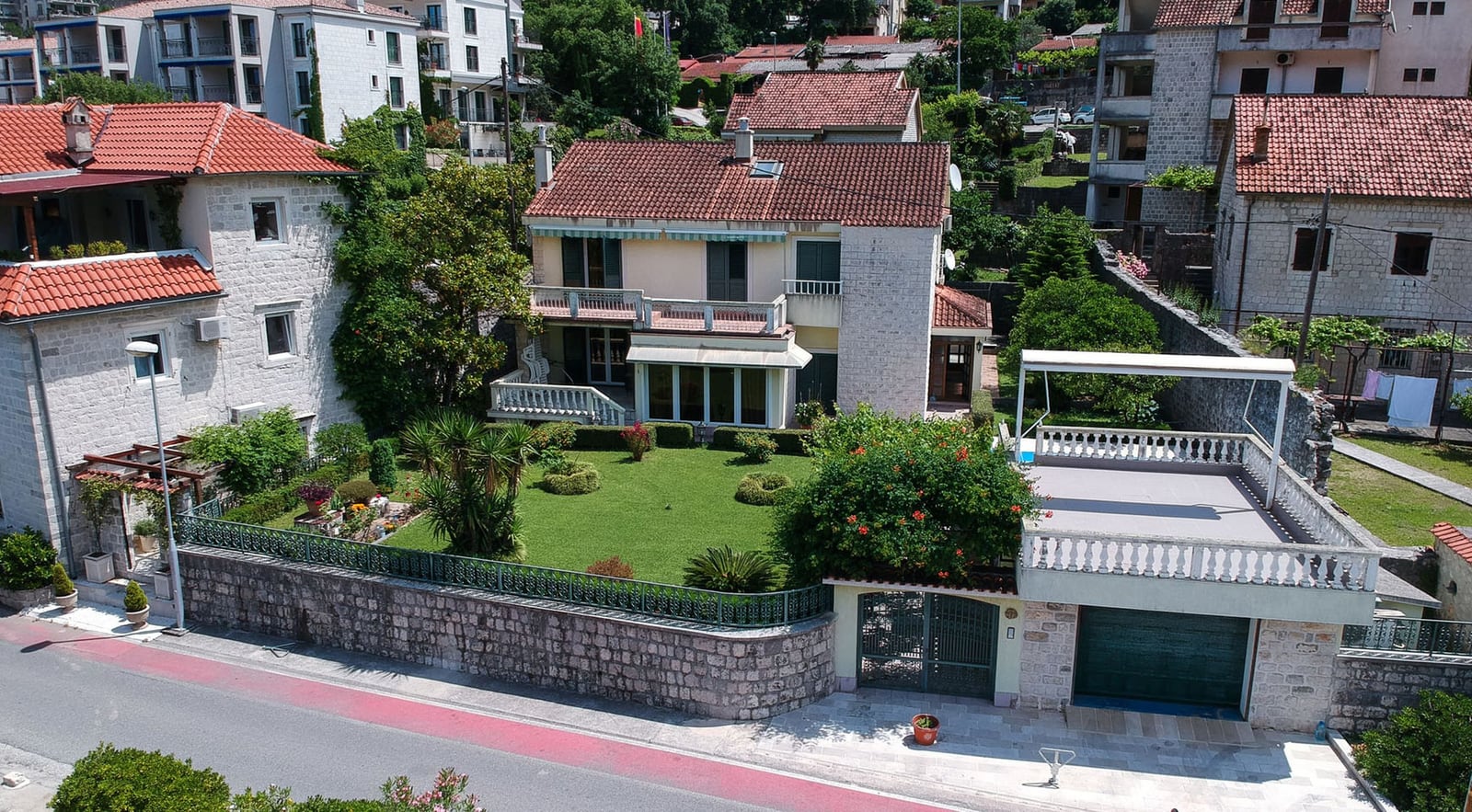 Two-story villa in Dobrota, Montenegro, with a well-kept garden, terrace, stone finish, and garage.