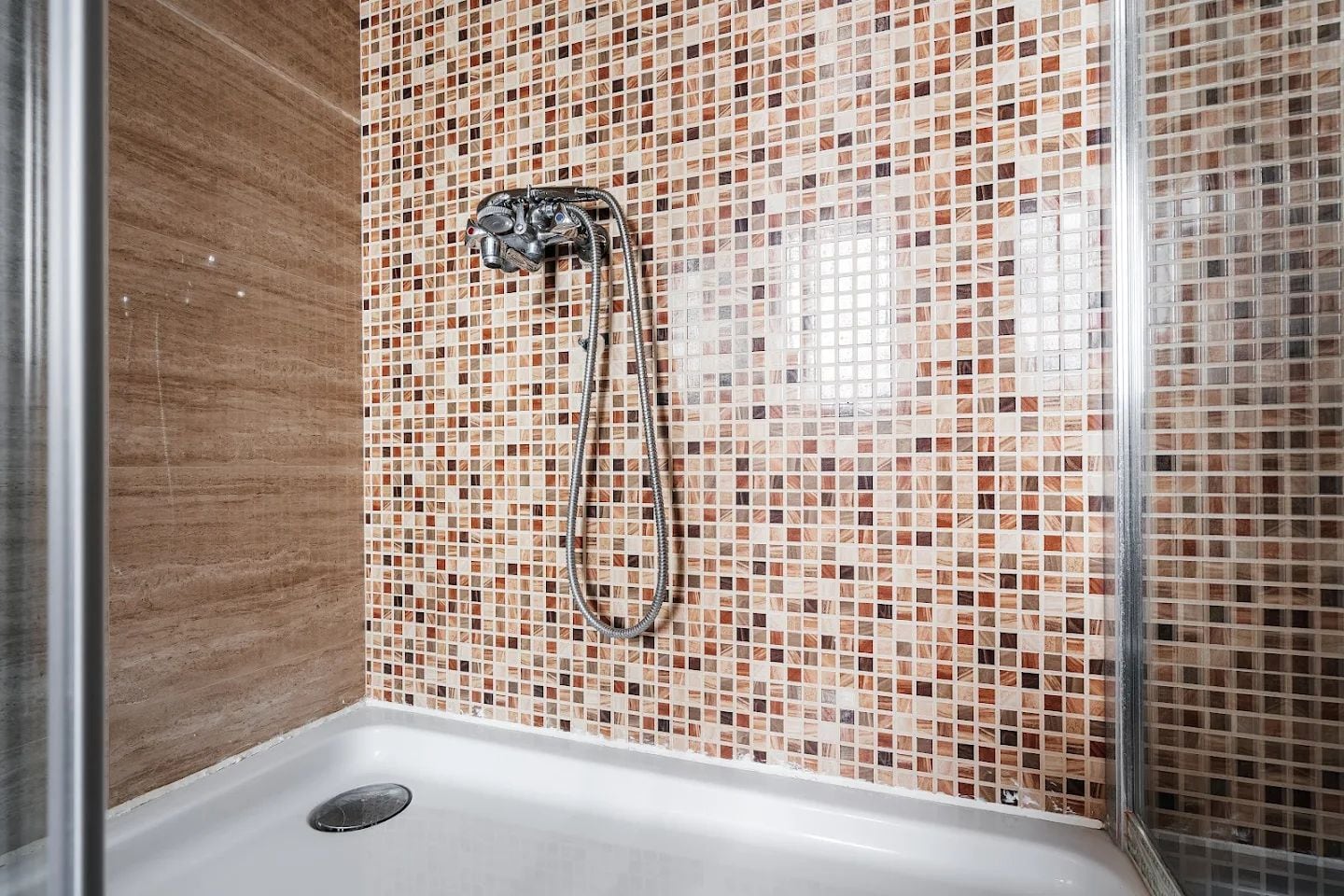 Shower cabin with mosaic tile and a white tray in an apartment, Budva, Montenegro. Modern bathroom finish.