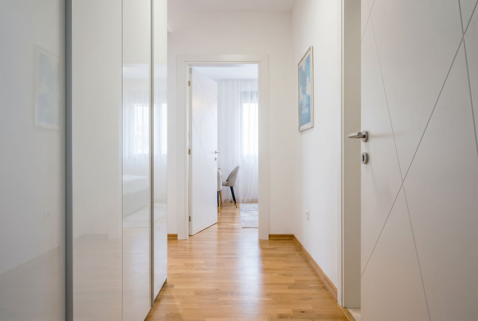 Bright hallway in a modern apartment in Tivat, Montenegro: parquet flooring, built-in wardrobe, and white interior doors.
