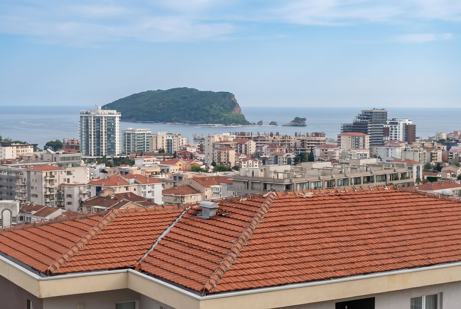 Panoramic view of Budva city, tiled roofs, and the island of St. Nicholas in Montenegro