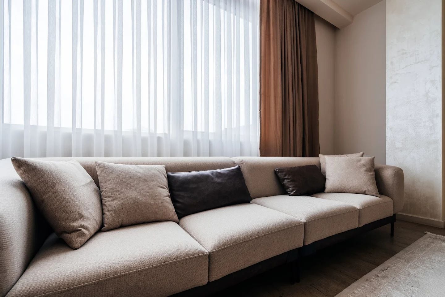 Bright living room with a beige sofa and panoramic window in a modern apartment, Budva, Montenegro.