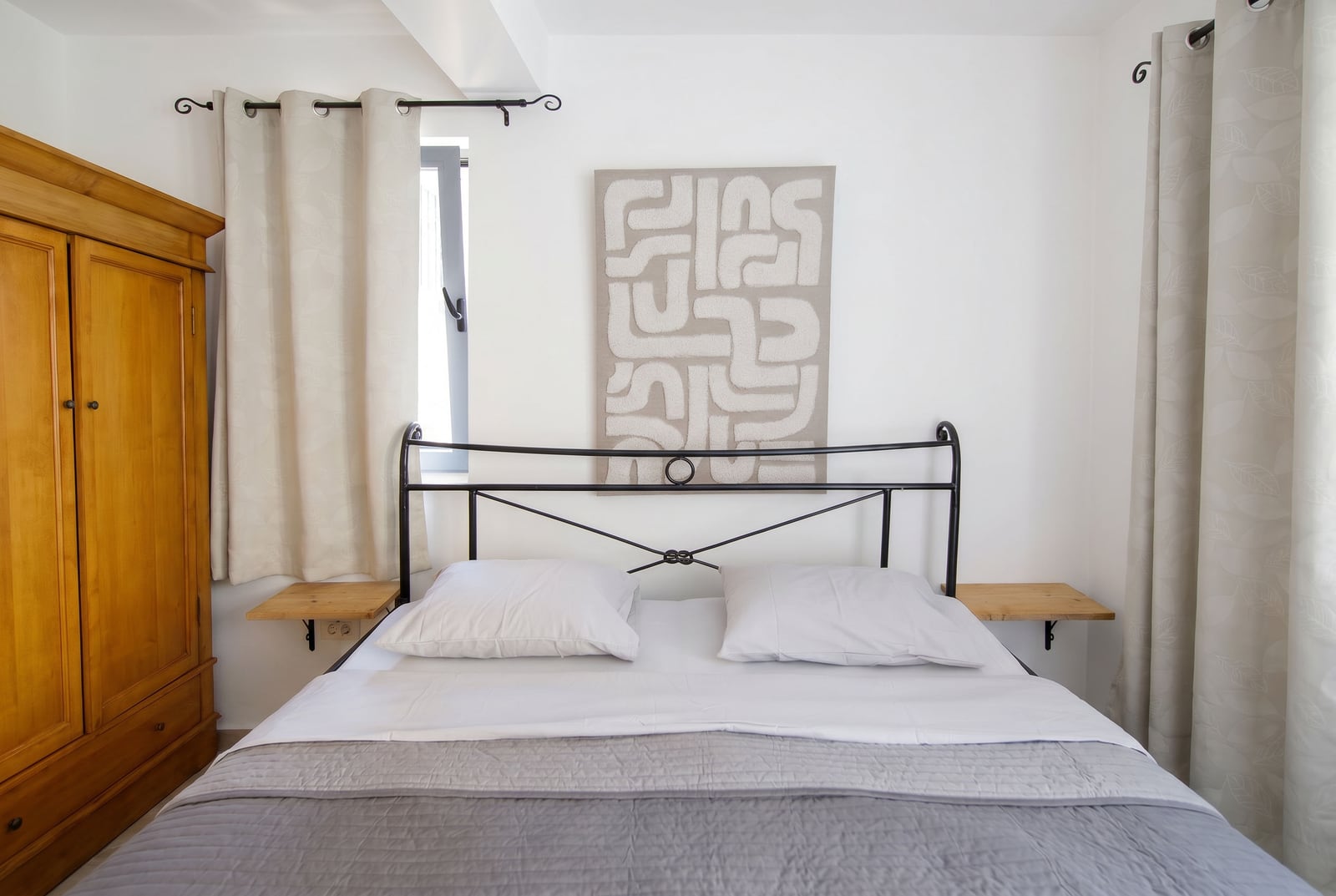 Bedroom in an apartment in Risan, Montenegro: a double bed with a wrought iron headboard, a wooden wardrobe, and wall decor.