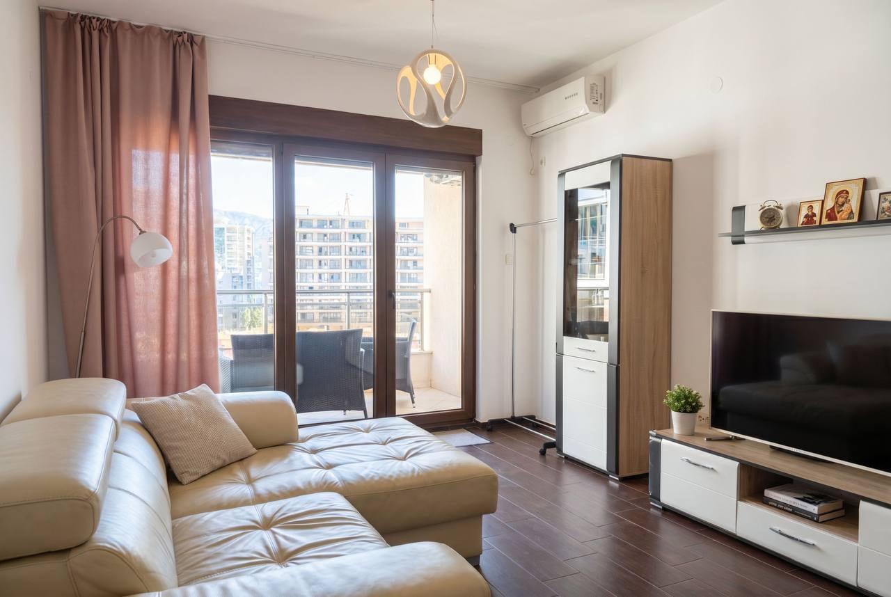 Living room with a leather sofa and terrace access in an apartment, Budva, Montenegro. Modern interior with a TV area.