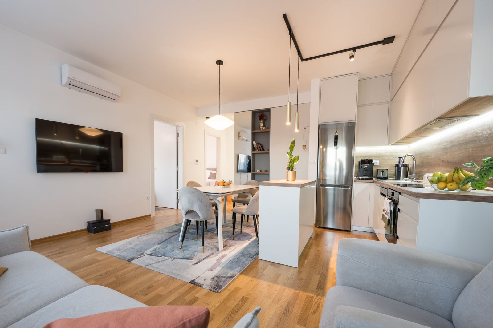 Modern living room with an open-plan kitchen in a Tivat apartment, Montenegro: bright interior, dining area, and new appliances.