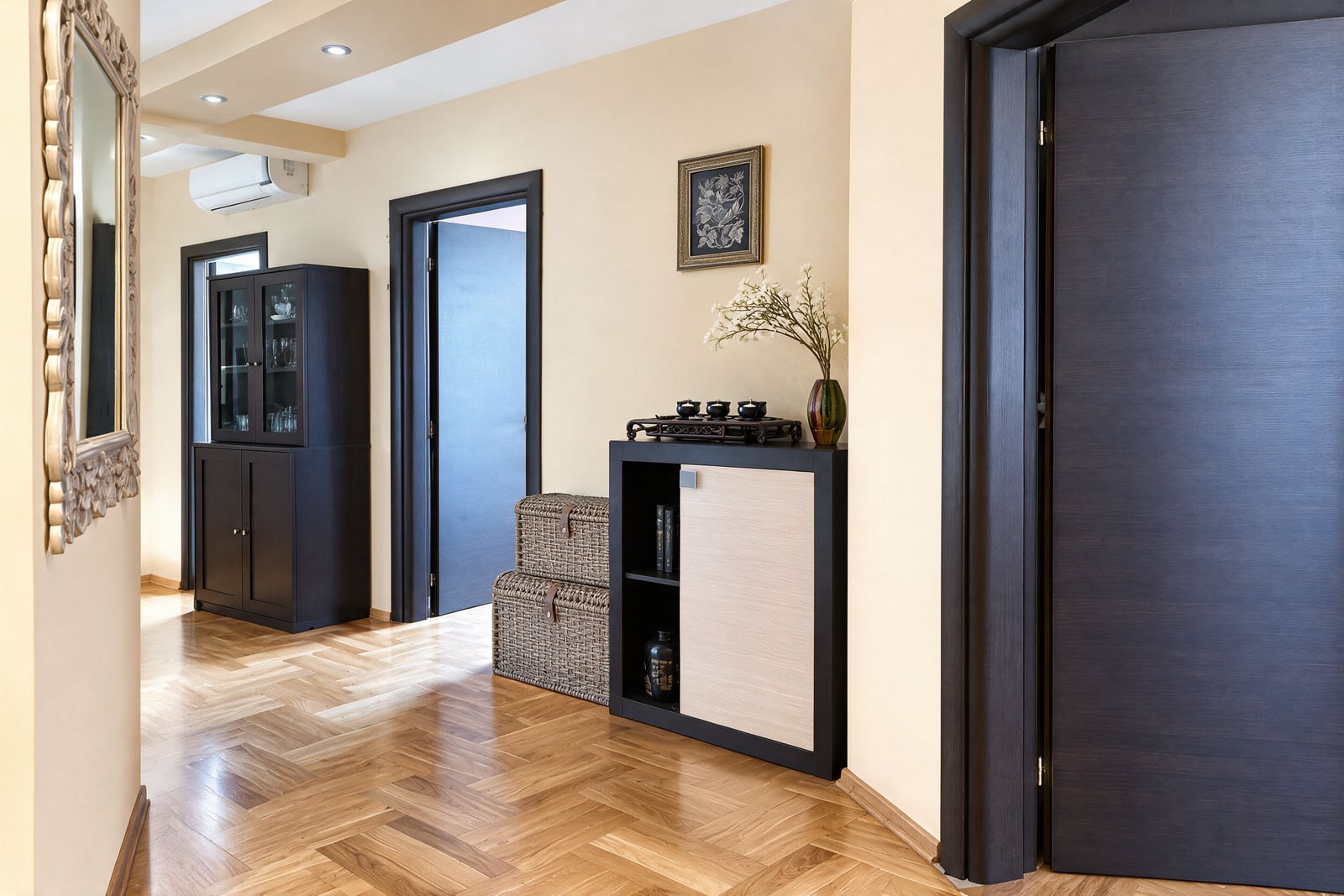 Entryway with herringbone wood floors, dark furniture, an ornate mirror, and woven storage baskets against the wall.