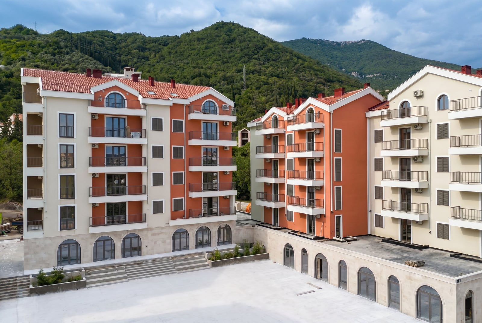 Modern residential complex with terraces and mountain views in Tivat, Montenegro. Building facade with panoramic windows.
